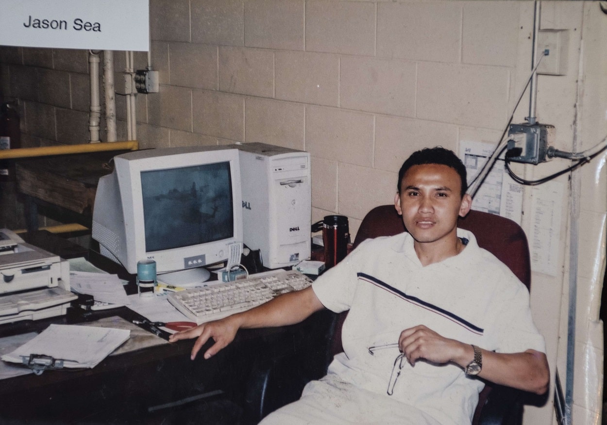 older photo of young man sitting at desk with computer