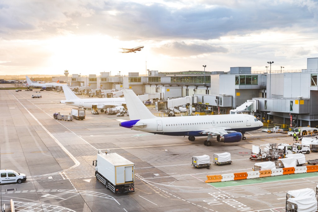 busy-airport-view-with-airplanes-and-service-vehicles-at-sunset-picture-id