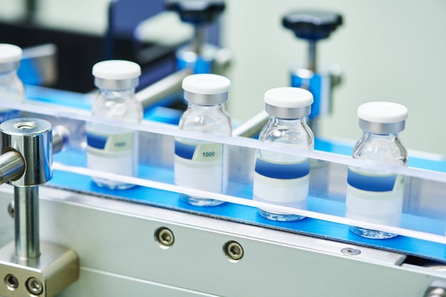 vials of vaccine on a conveyor belt at a pharmaceutical plant