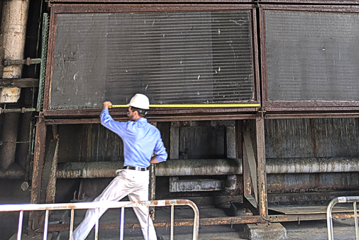 Engineer measuring industrial heat exchanger on-site