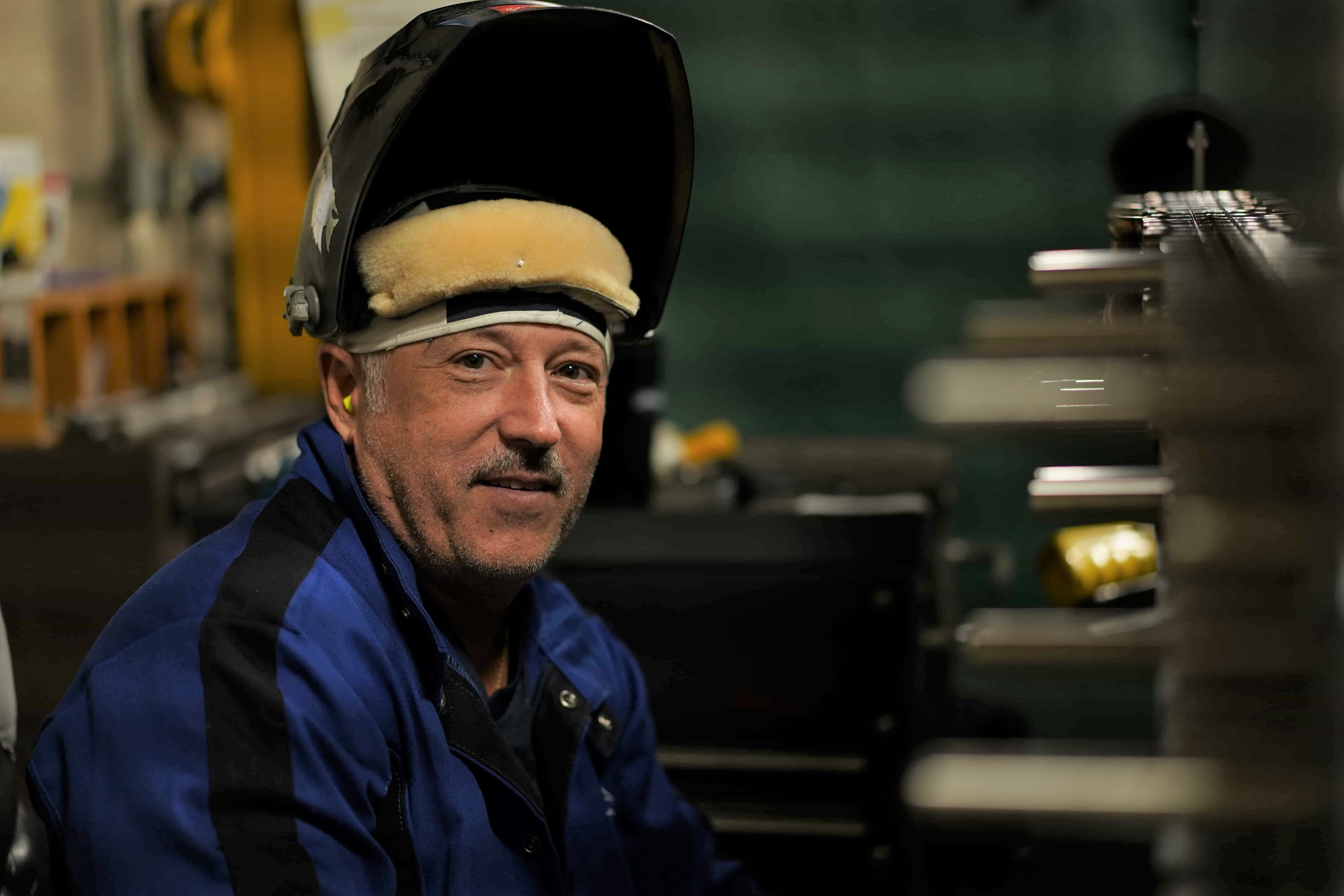 Male welder with helmet off looking towards camera