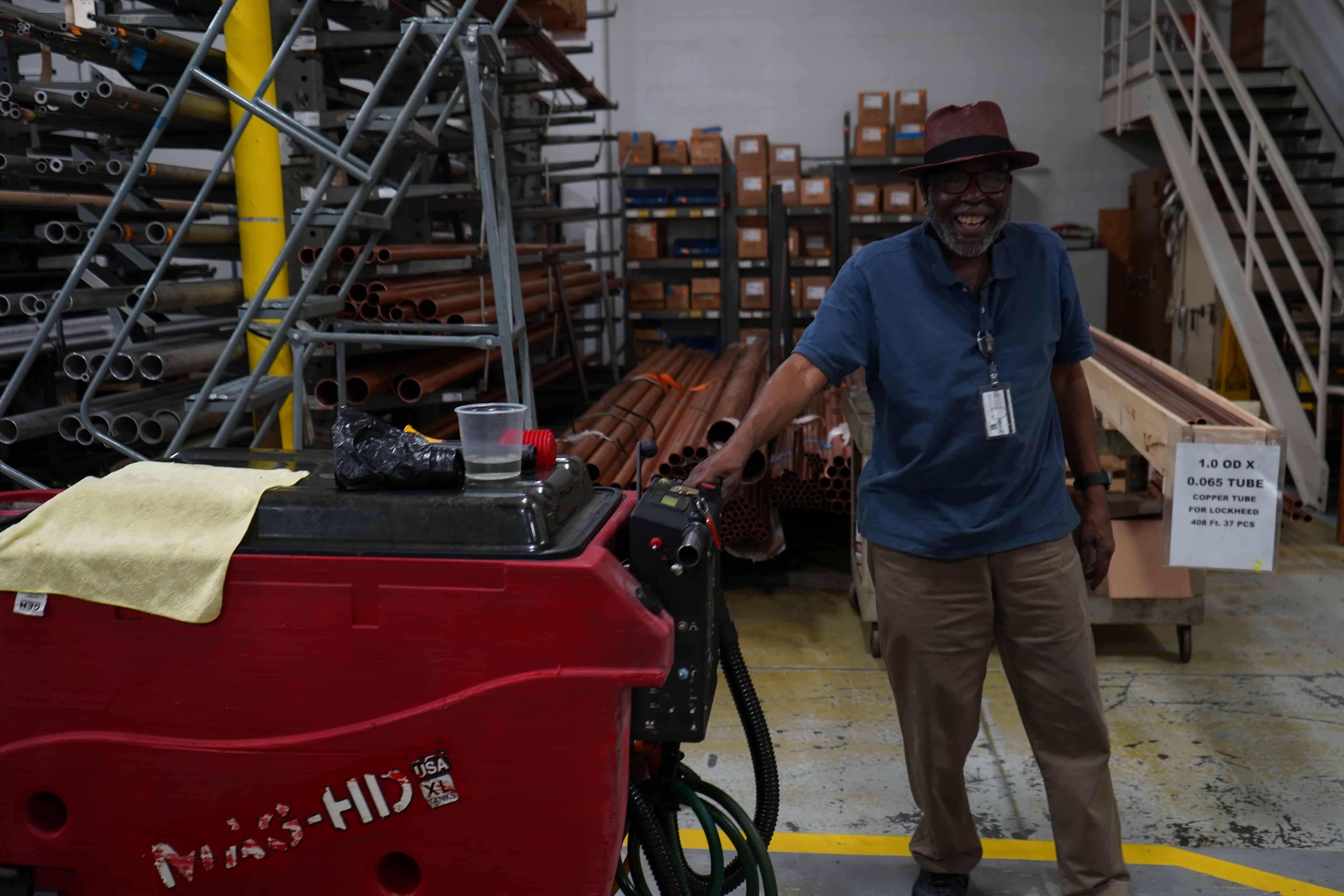 man with floor cleaning machine smiling at camera