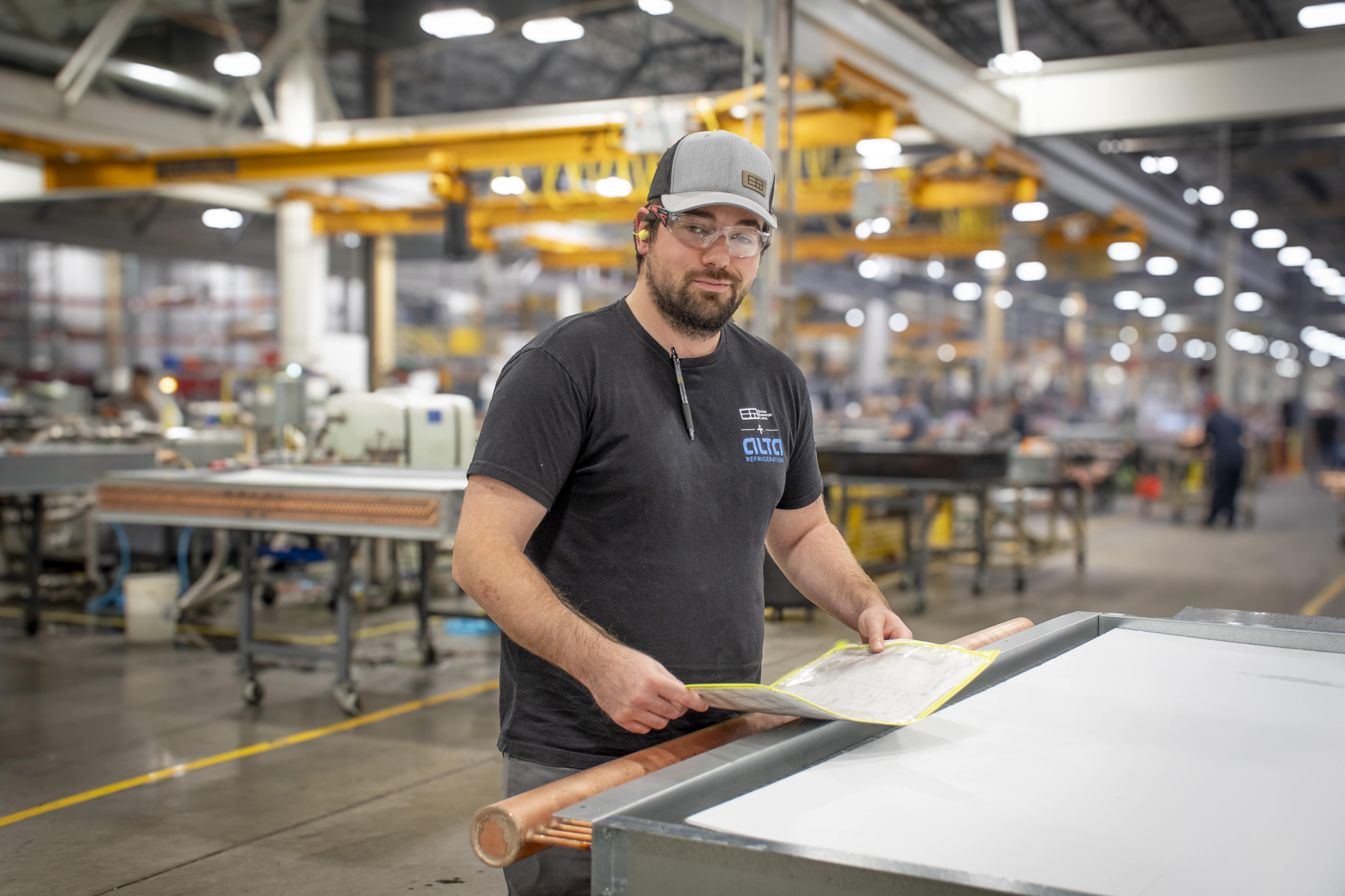 man standing in manufacturing facility holding blueprints