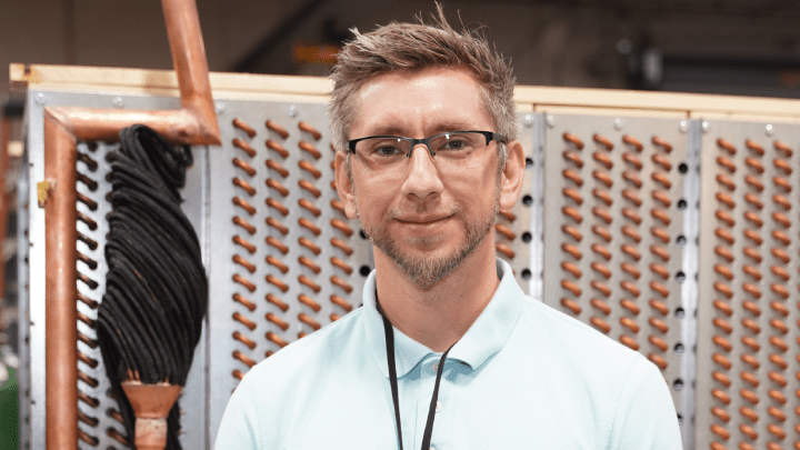 man with glasses standing in front of coil