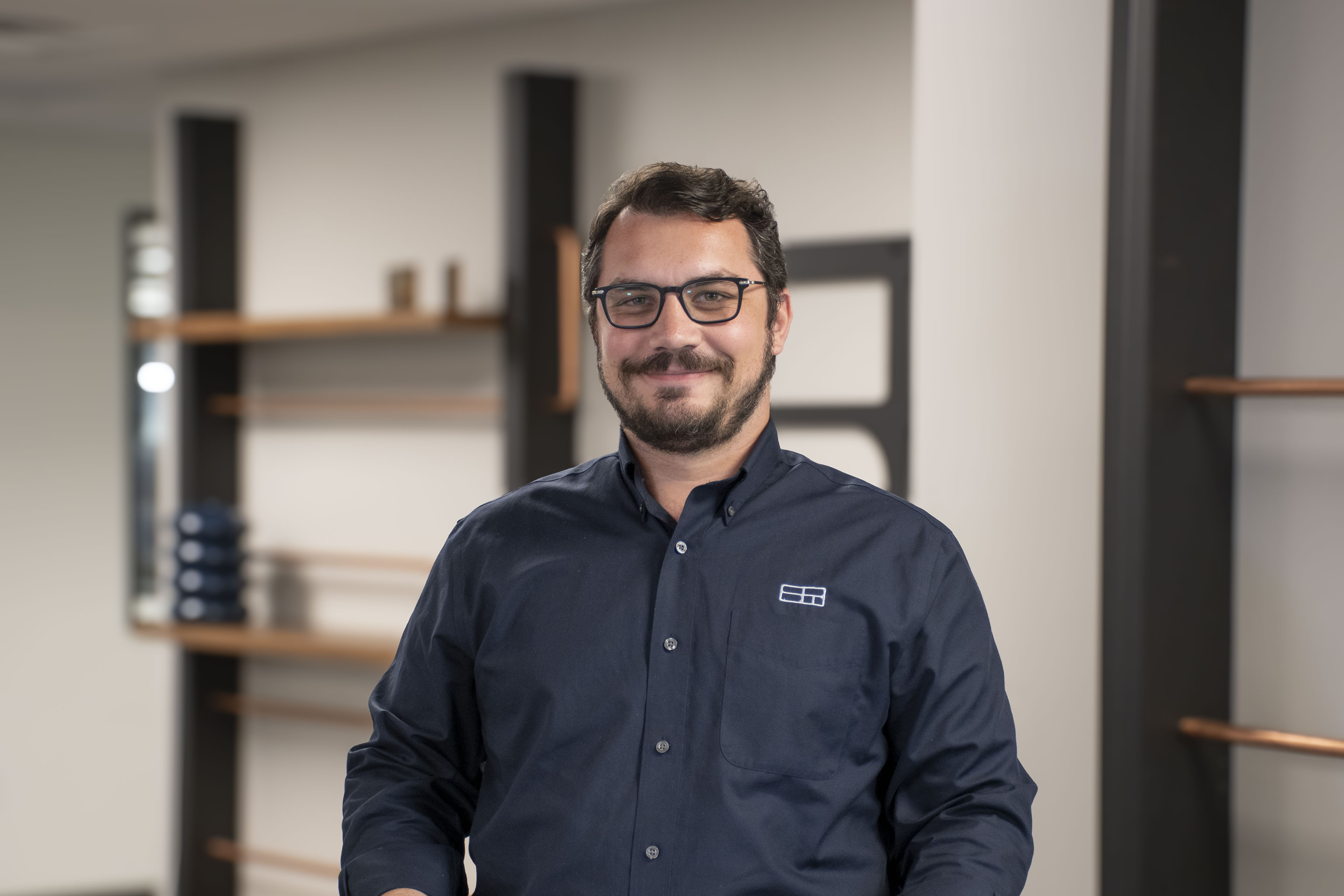 man with glasses and facial hair posing for official office photo