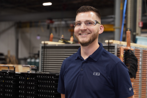 man in blue shirt standing by coils