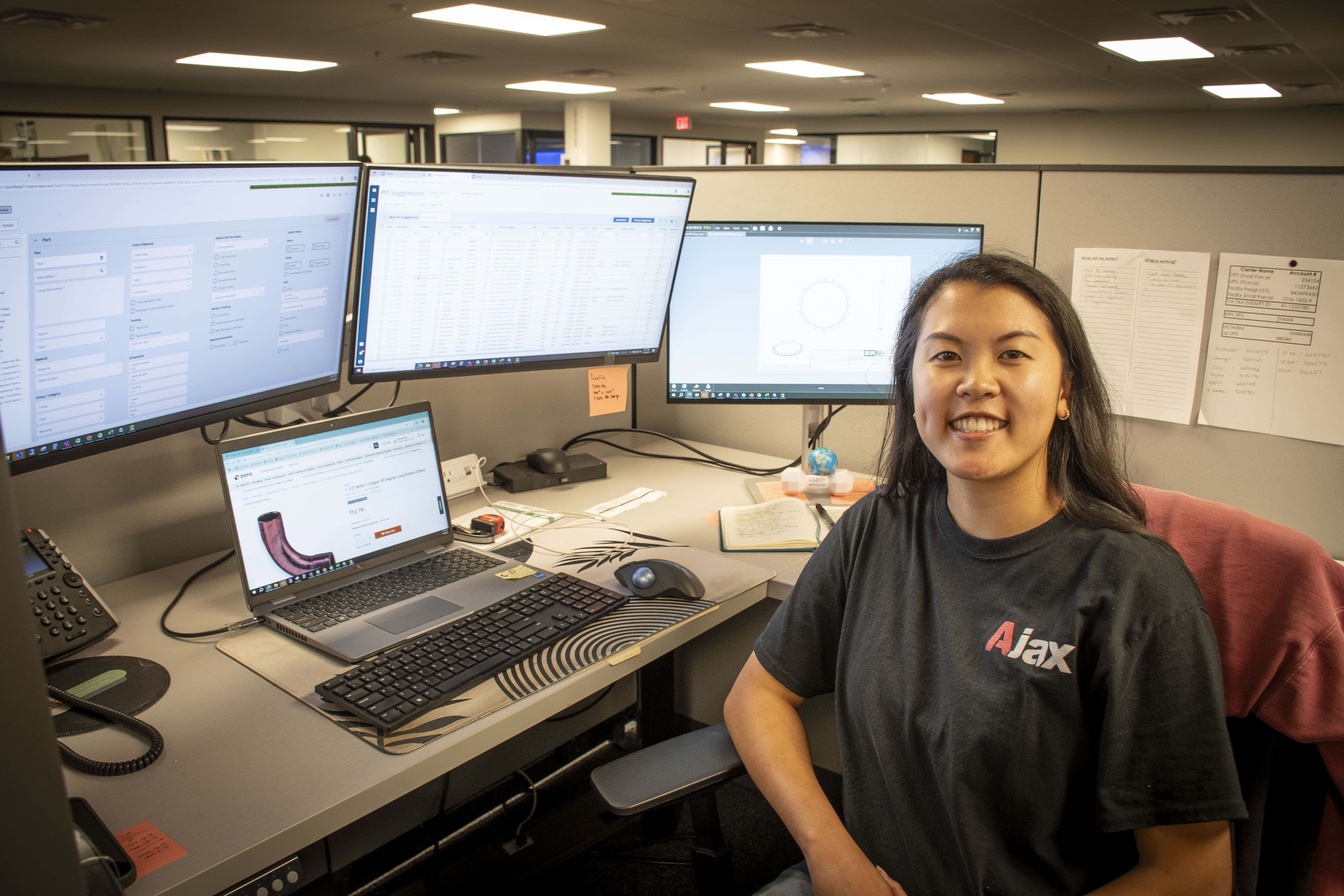 woman sitting at desk with computer monitors and smiling for camera