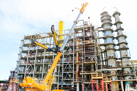 large oil refinery with industrial crane in the foreground